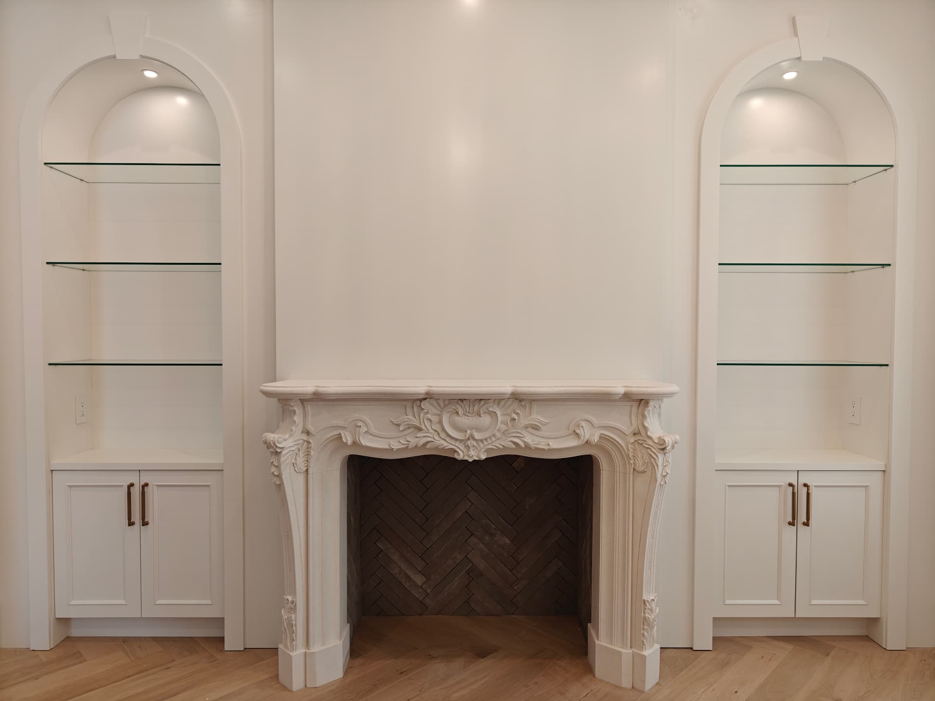 Ornate hand-carved Bordeaux limestone fireplace mantel in a paneled living room with built-in shelving